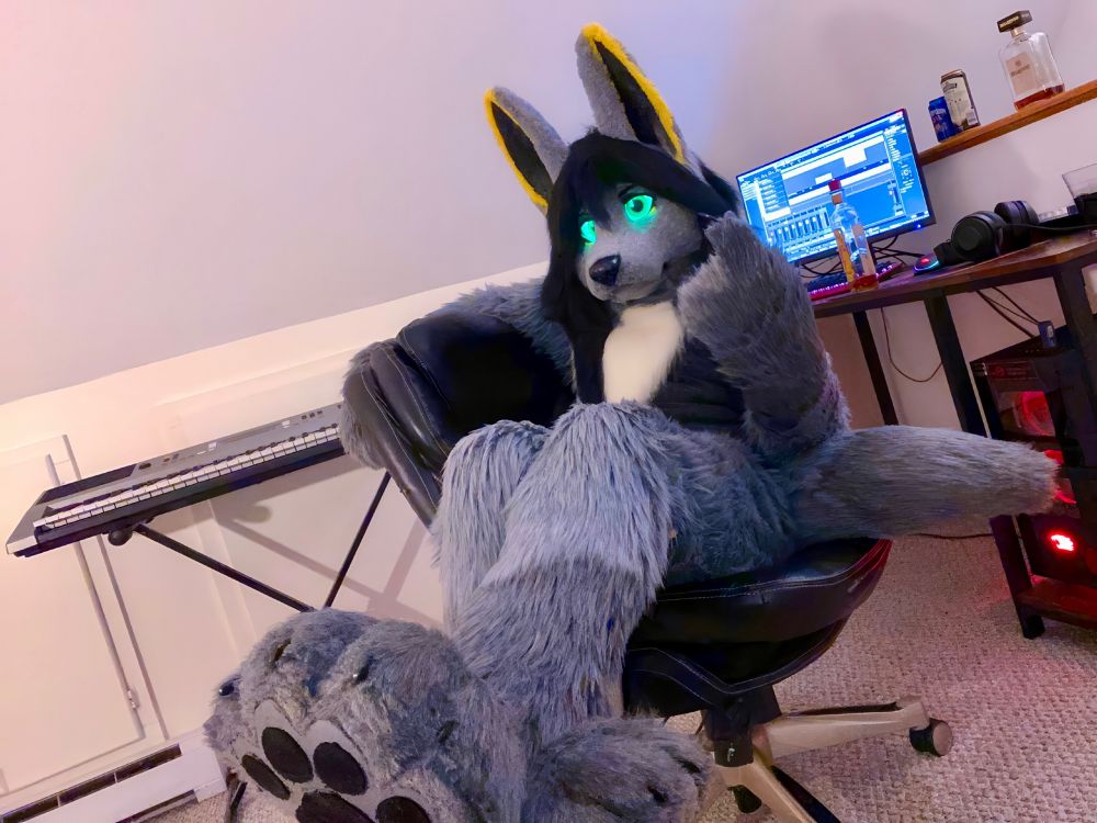 A handsome jackal fursuit lounging in his upstairs studio.