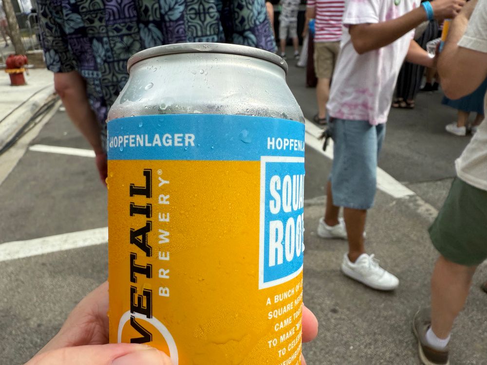 A hand holds a can of Dovetail Brewery Hopflenlager, brewed especially for Square Roots Festival.