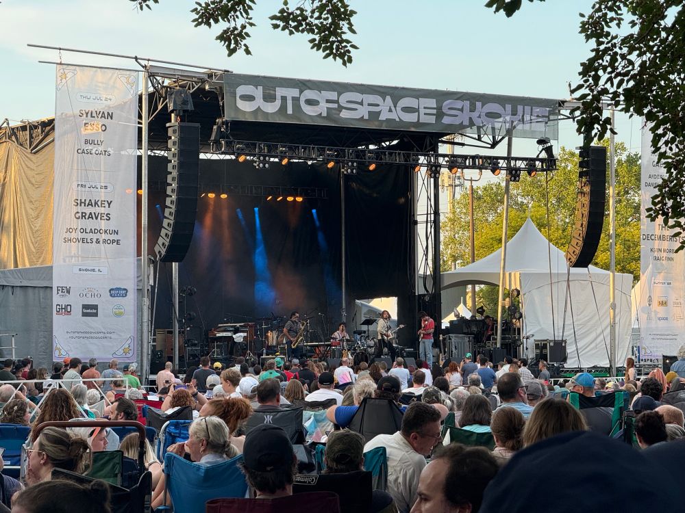 A distant view of Kevin Morby onstage at Out of Space at Searle Park in Skokie with a sea of people in lawn chairs between my vantage point and the stage. 