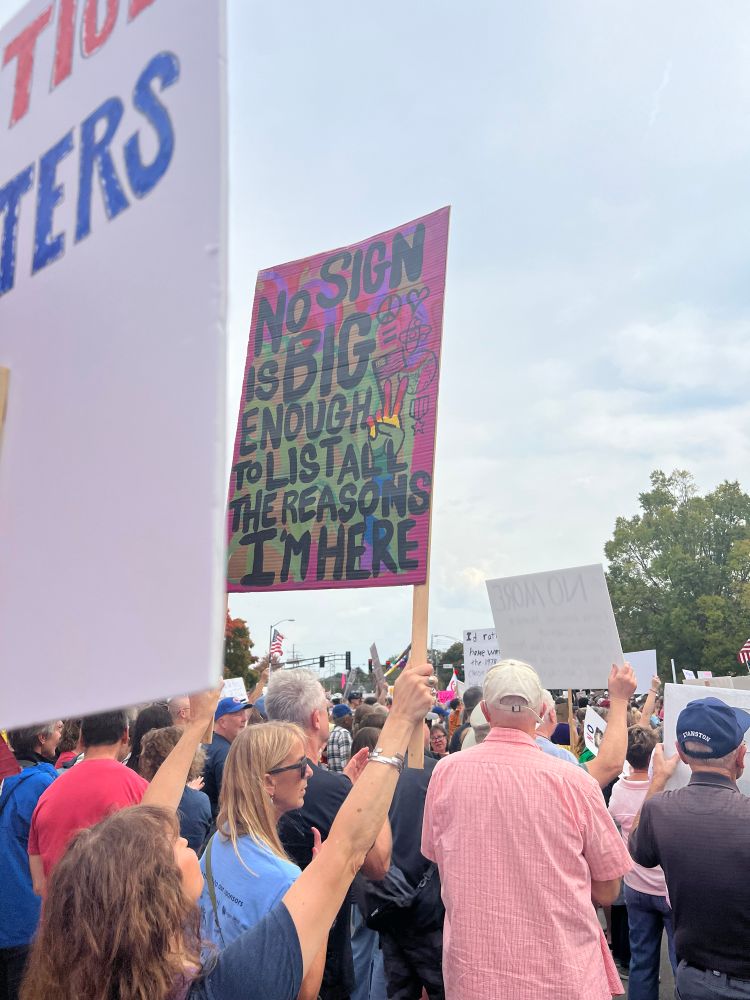 Protest sign held up in a large crowd of people that reads “No Sign is Big Enough to List All the Reasons I’m Here”