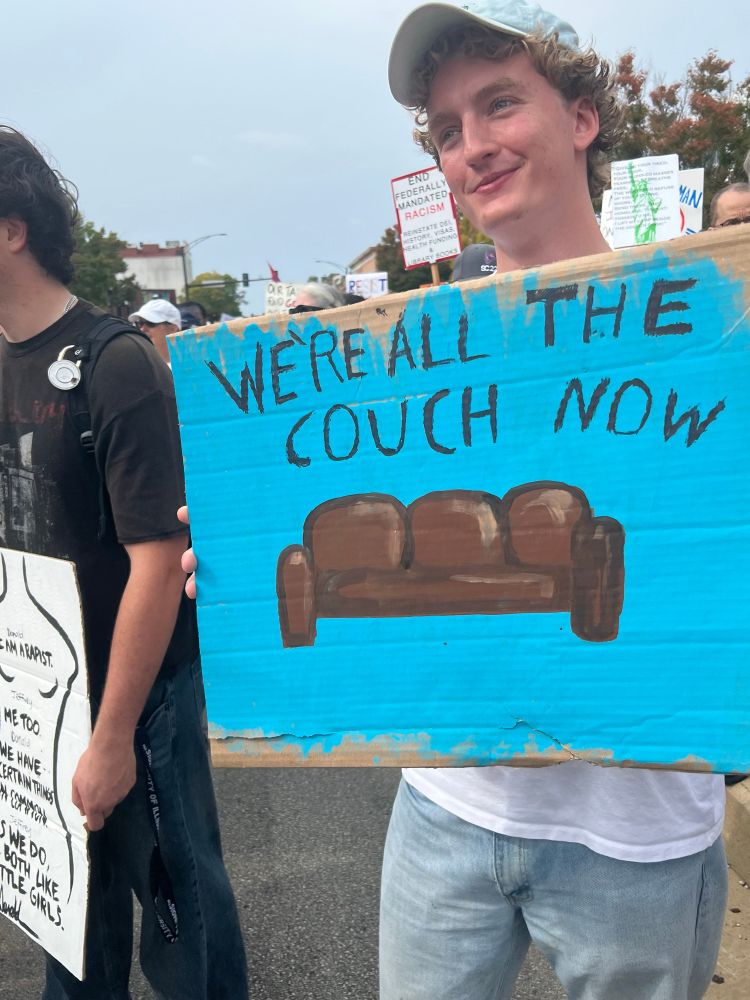 Protest sign “we’re all the couch now” held by a U of I student 