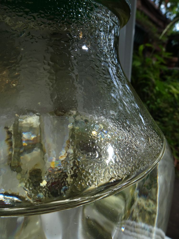 Milk bottle filled with water, standing in sunlight and shadow.