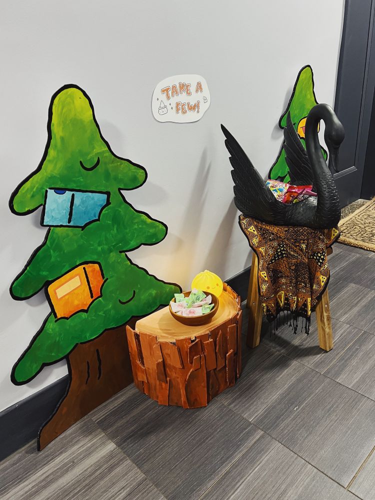 A little candy station outside of our apartment door featuring the painted stump and trees from my Faraway Forest window display, plus bowls of candy 
