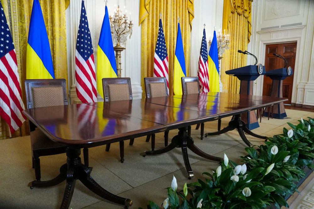 a large table in an empty room with US and Ukrainian flags
