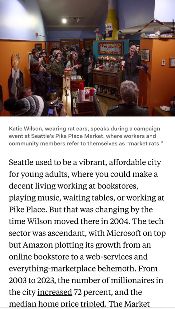 a screenshot excerpt of the article with an image of Katie Wilson, wearing rat ears for Halloween, speaking during a campaign event at Seattle's Pike Place Market, where workers and communities refer to themselves as "Market rats"