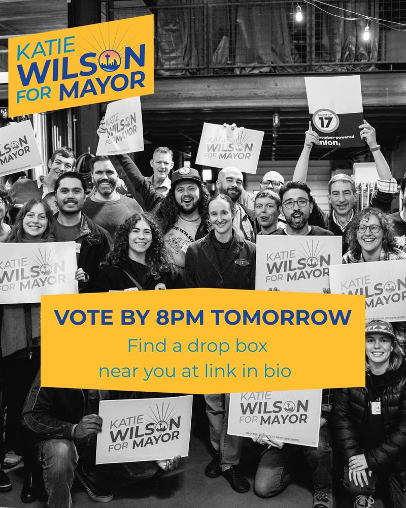 a Katie Wilson for mayor campaign graphic featuring a black and white photo of Katie Wilson surrounded by supporters, holding a campaign signs smiling for a group photograph. a text banner says vote by 8:00 p.m. Tomorrow find a Dropbox near you at Link in bio