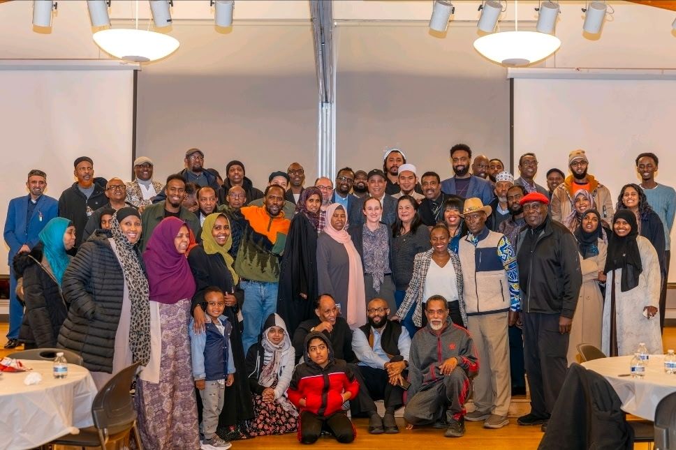 A photo of the organizers, leaders, and community members posing for a photo with Katie Wilson at the new Holly community center. the group consists of about 30 to 40 people