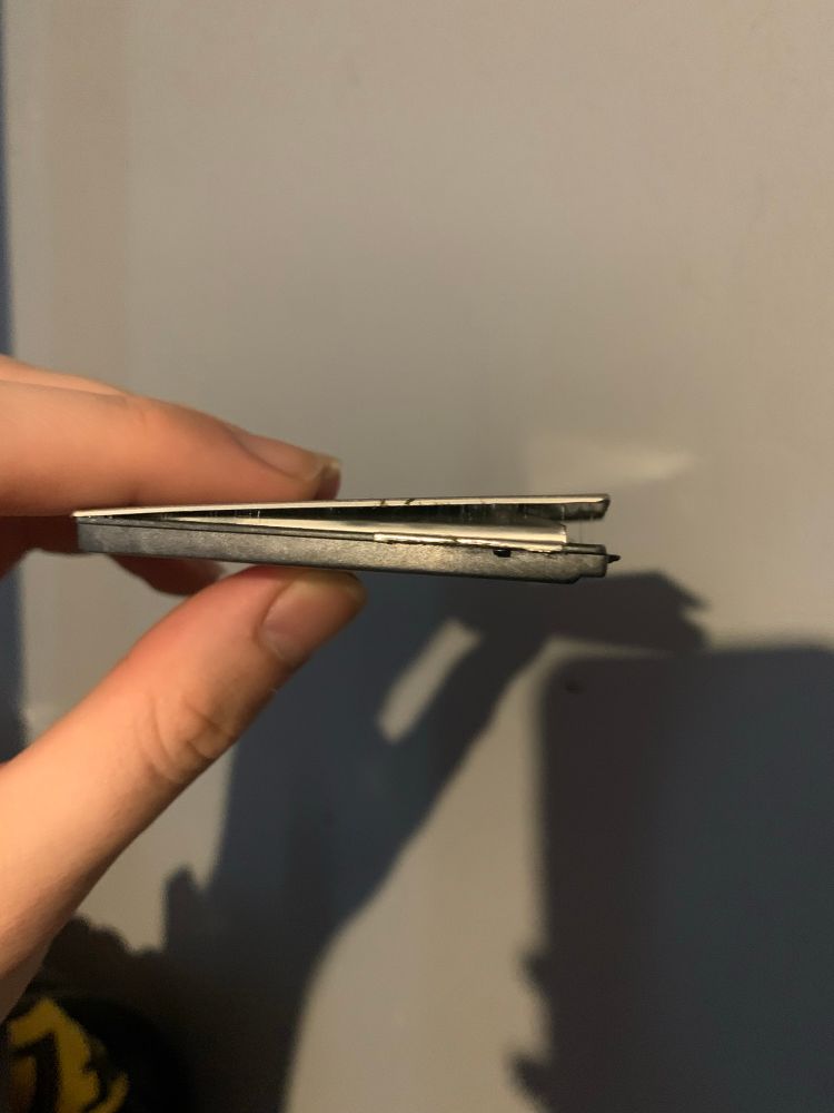 Holding a swollen lithium-ion cell, it’s pushing out of its enclosure due to how swollen it is.