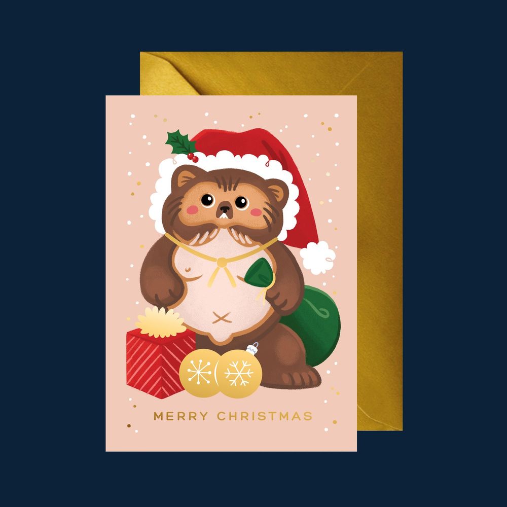 A mocked up image depicting a Christmas card. The card is cream in colour and features a cute pink-cheeked tanuki dressed in a Santa Claus hat, holding a green sack of presents. There are two golden Christmas baubles sitting between his feet.