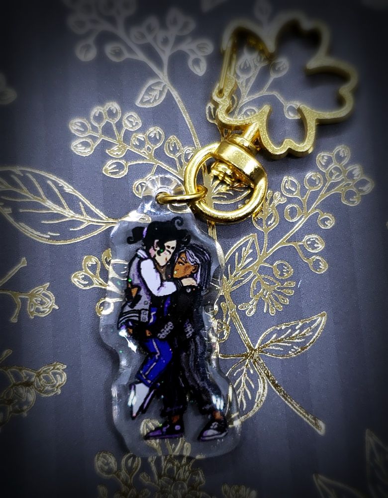 An acrylic charm of Glenn Close and Morgan Freeman from the TTRPG live play podcast Dungeons and Daddies. The charm has an epoxy layer that gives it a slightly rounded dome and a faint glitter finish.