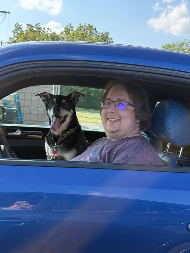 A picture outside my Beetle showing me in the driver seat and my dog Rusty in the passenger seat