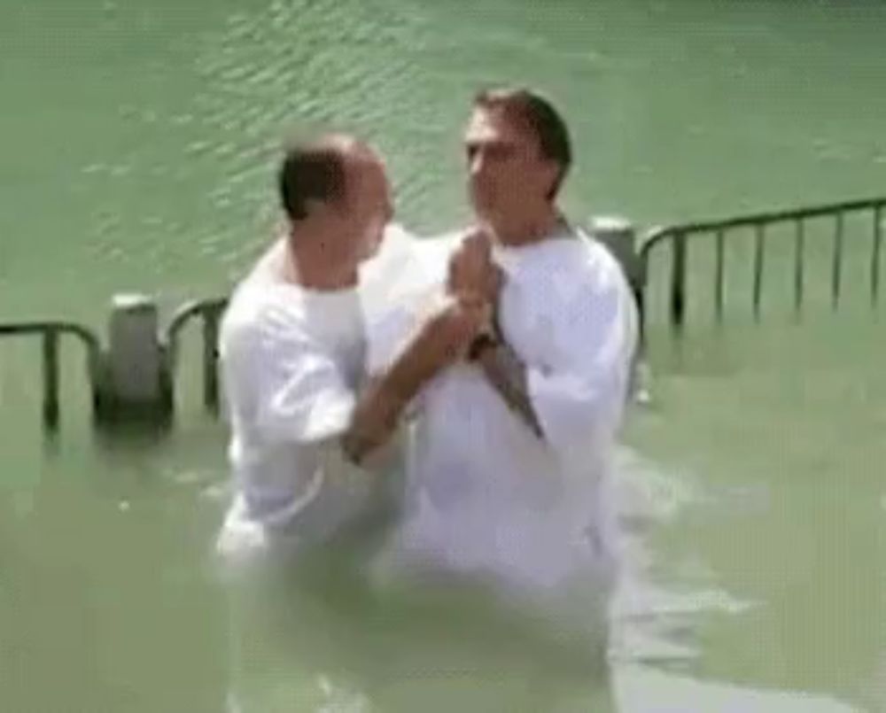 a man is baptising a child in a lake