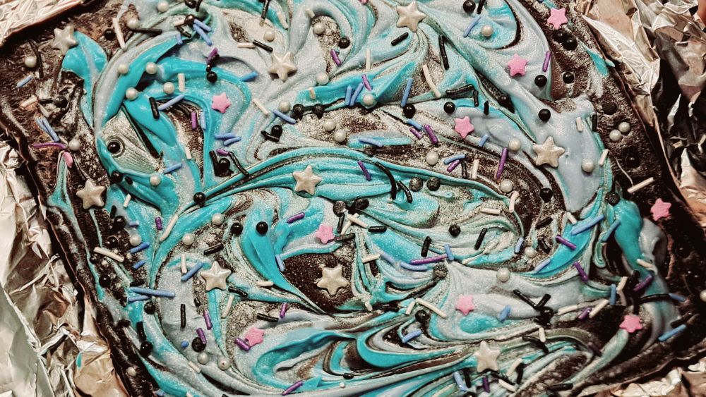 Chocolate bark candy with swirls of blue and purple melted candy, covered in starry sprinkles and edible glitter!