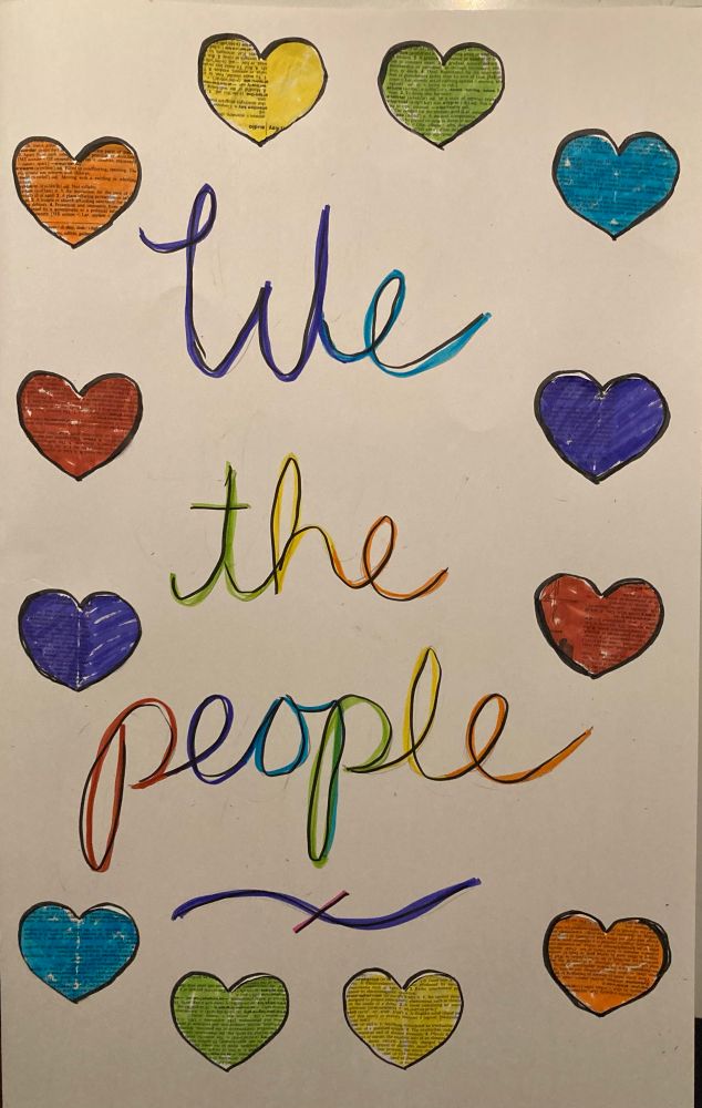 Protest sign that reads: We the people, surrounded by hearts, all in rainbow colors.