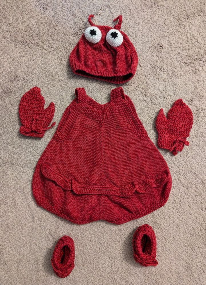 A baby lobster costume - red romper, claw gloves, booties, and hat with eye balls and antenna. The romper is flipped over to show the lobster tail ruffle detail on the butt.