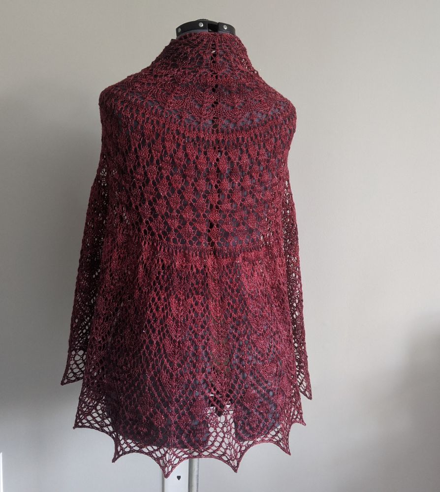 A red lace shawl draped over a sewing form