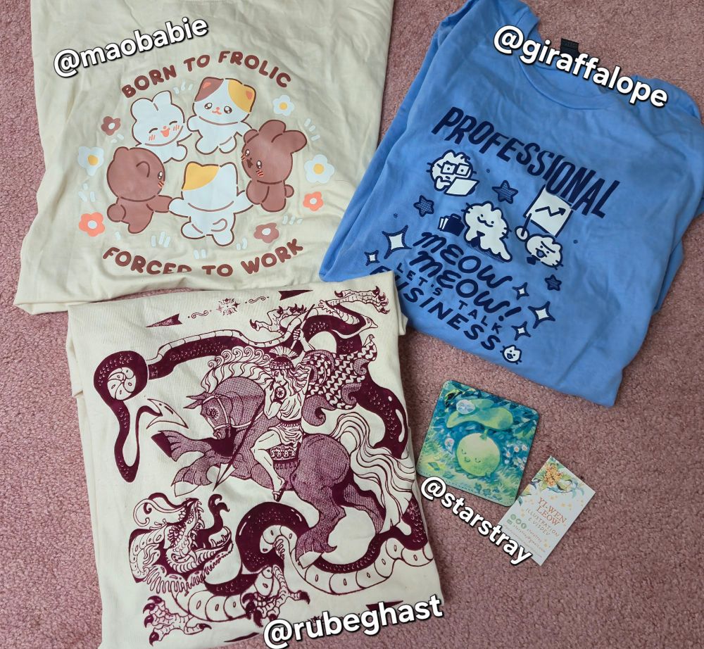 - A beige T-shirt with cute animals dancing in a circle with the caption, "Born to Frolic, Forced to Work" (by @Maobabie)
- A blue t-shirt with cats dressed as business people with the caption, "Professional meow meow! Let's talk business." (by @Giraffalope)
- A beige t-shirt with a gothic print of St. George and the Dragon (by @Rubeghast)
- A small drink coaster with a Korpokkur print (by @Starstray) 