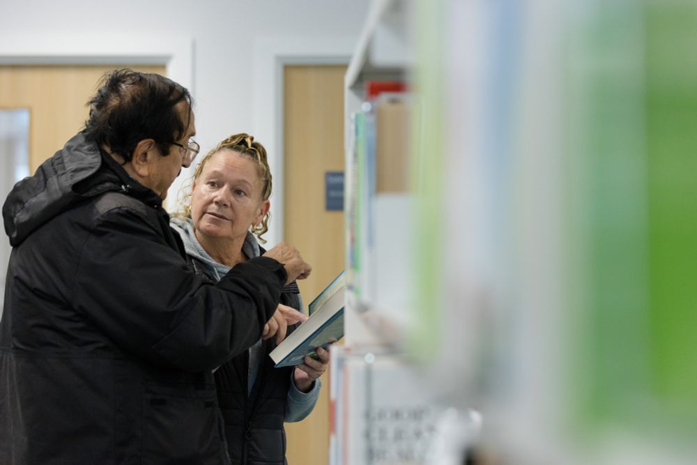 A female librarian shows a book to a man.