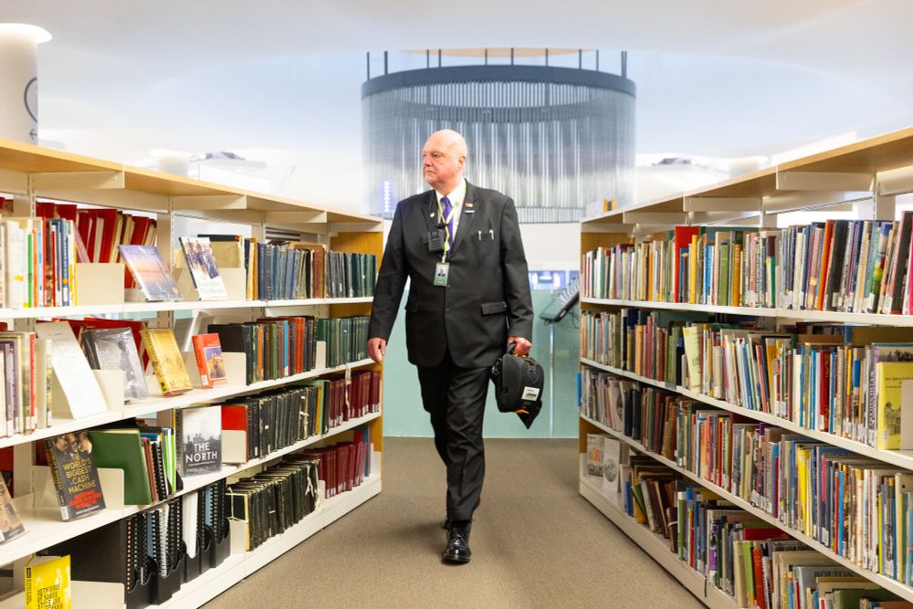 A man walks through a library surrounded by books.