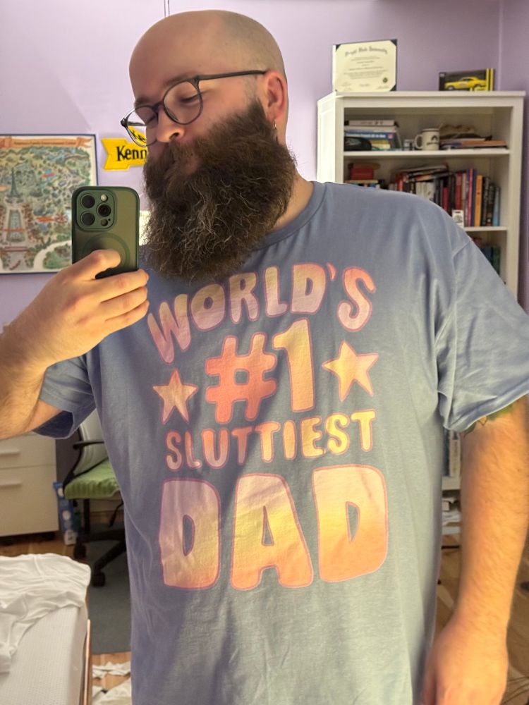A selfie of me in a mirror wearing a lavender shirt that says, "World's #1 sluttiest dad"