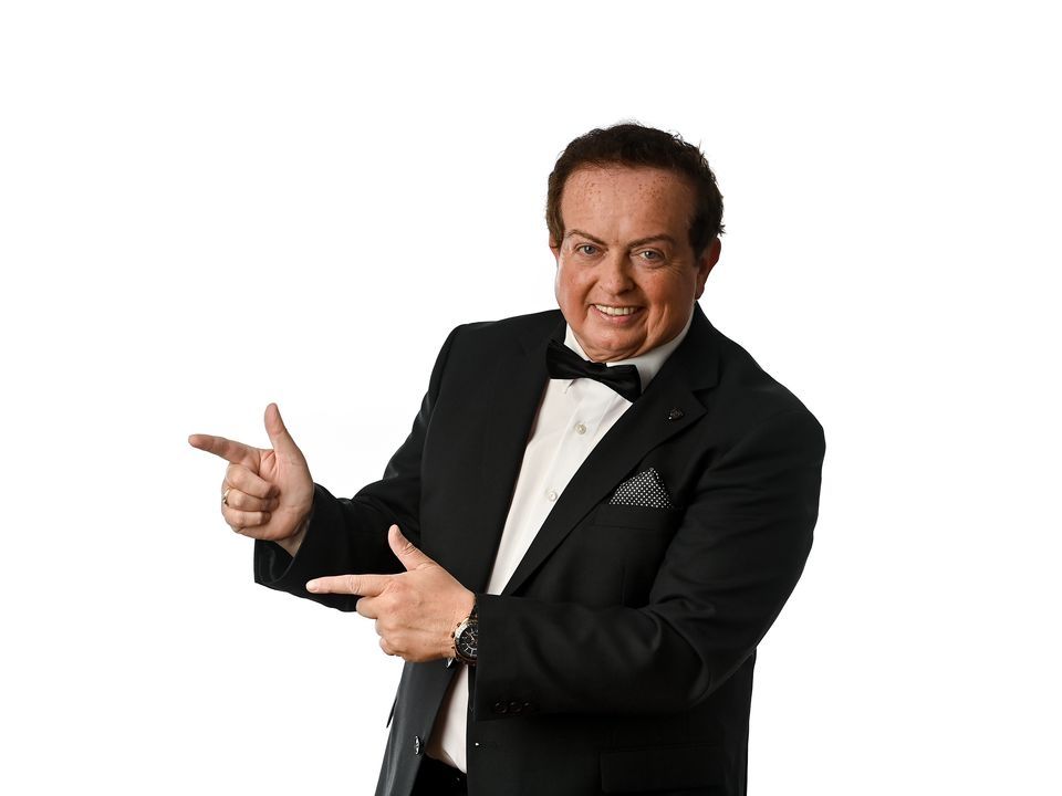 Marty Morrissey in a tux brandishing finger guns. 