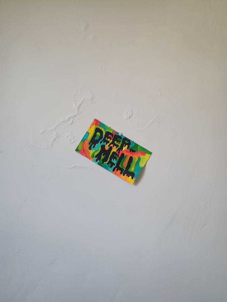 white plaster backboard, single canvas flier of dripping black runny horror text over a drifting tie dye background. words read "deep - hell" 