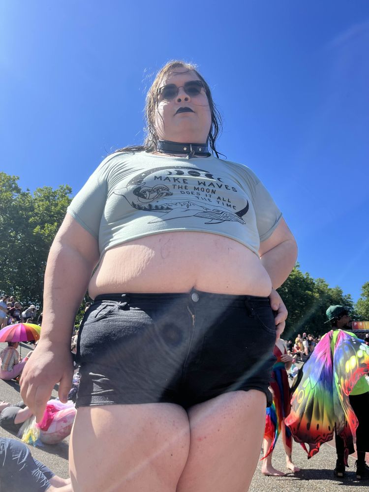 A shot of Josie from below in a crop top and tiny shorts, a collar around her neck