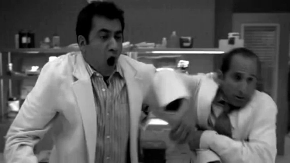 a black and white photo of two men in lab coats and ties fighting