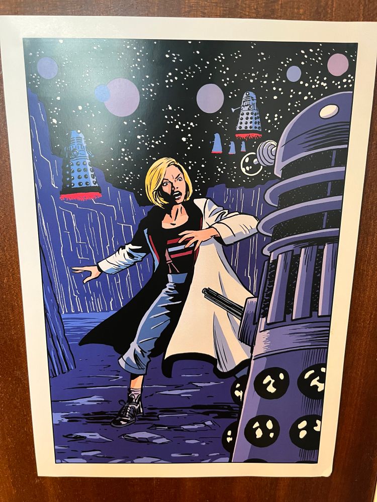 The Thirteenth Doctor looks annoyed as a group of Daleks surround her.