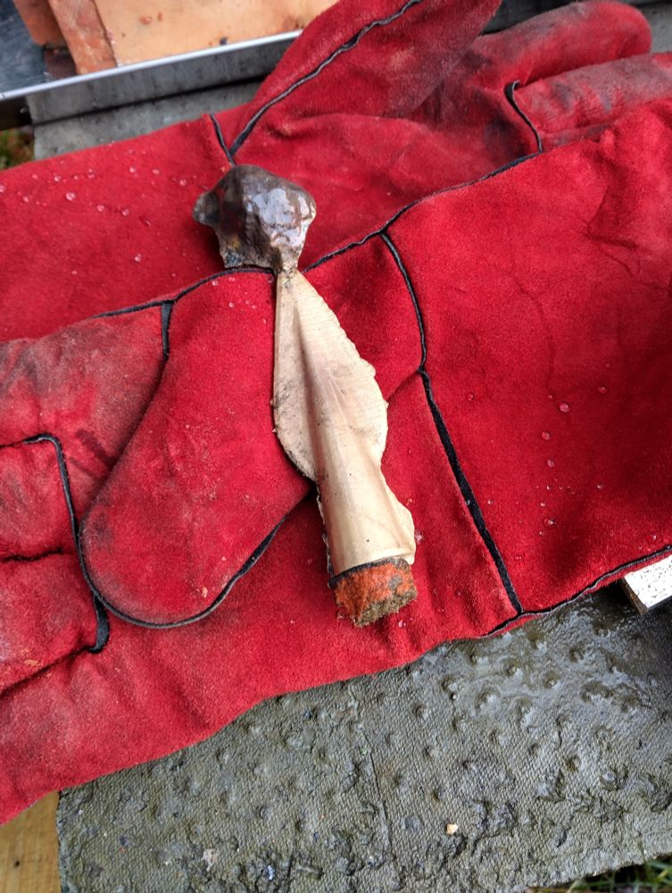 A bronze spear head, just cast with the sprue still attached 