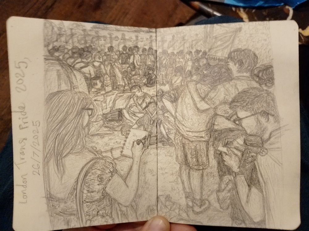 Graphite pencil sketch across two A5 pages of a small sketchbook. Sketch is of a crowd of people listening to speeches at London Trans Pride 2025. Two people in the foreground are sketching and two people in the midground are embracing. Further back, two groups of people sit in circles on the ground and many people are standing closer to the flags and trees in the background. Some people are wearing large pride flags. 