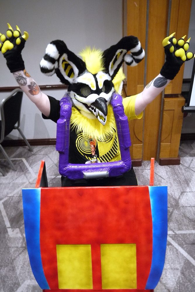 A gryphon fursuit sitting inside a rollercoaster train prop