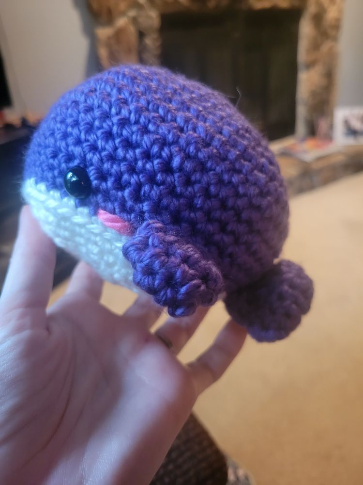 a small, fat purple whale amigurumi with blushing cheeks. it is extremely cute.