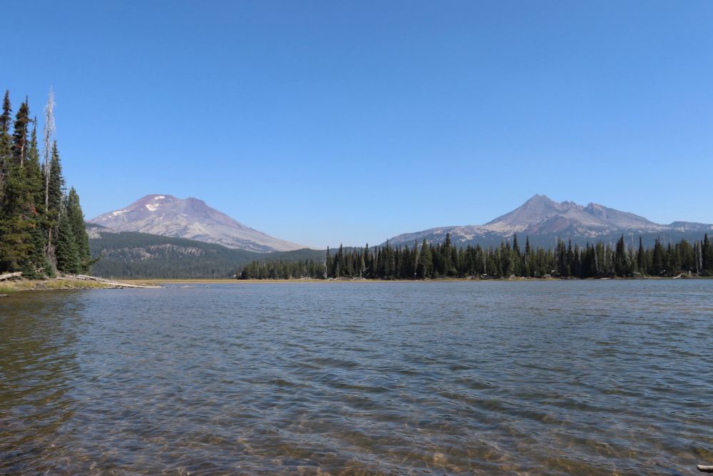 A landscape photo with a lake in the foreground and two large mountains in the background