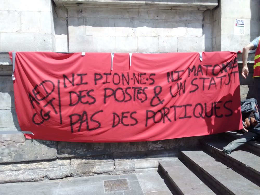 Banderole « AED CGT ni pion·ne·s ni maton·ne·s / des postes et un statut, pas des portiques « 