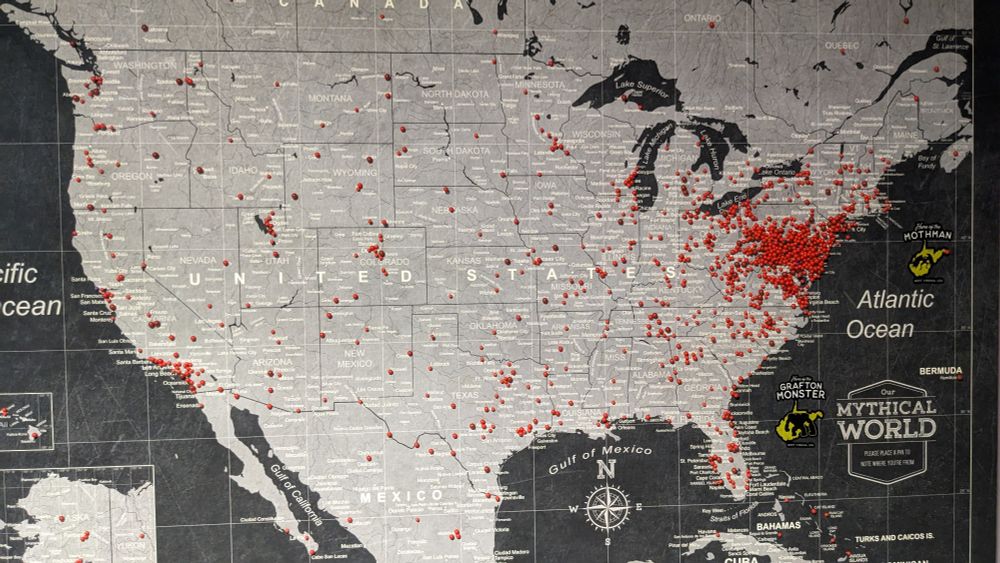 A large map of the United States with red pins of cryptid sightings across it.