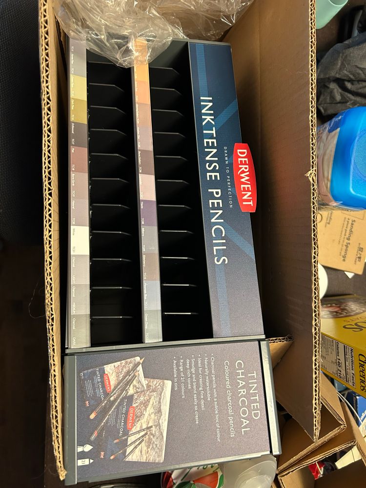 A shipping box containing an empty display case for Derwent Inktense and Tinted Charcoal pencils. As in, the display container they sell open stock pencils from in the store. 