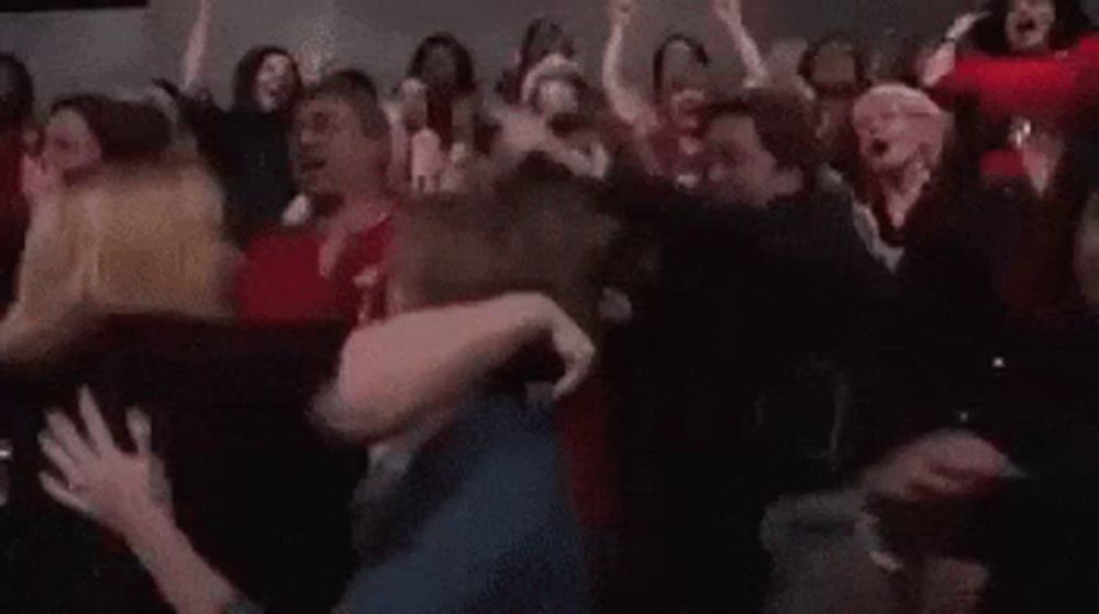 a crowd of people are dancing in a dark room and one woman is screaming .