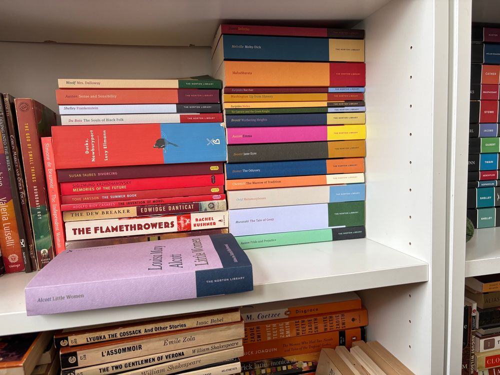 A collection of colorful Norton Library editions with an emphasis on the lilac and navy edition of Little Women