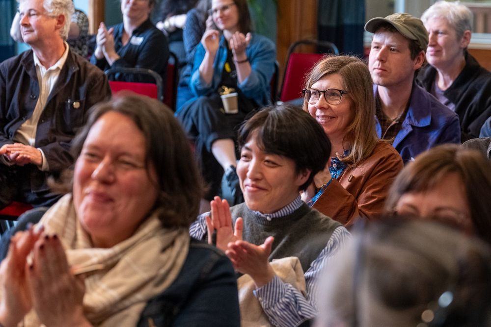 an audience sat facing foward, clapping and looking happy