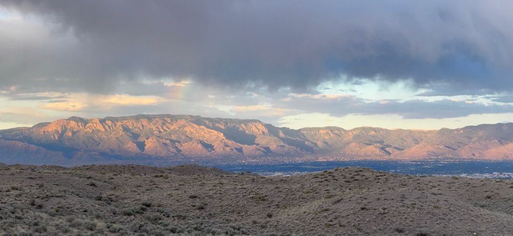 Looking east towards the Sandia Mountains, which are reflecting the setting sun light. The Petroglyph National Monument is in the foreground.  Between the Sandia Mountains and the Petroglyphs is the Rio Grande river valley and Albuquerque.