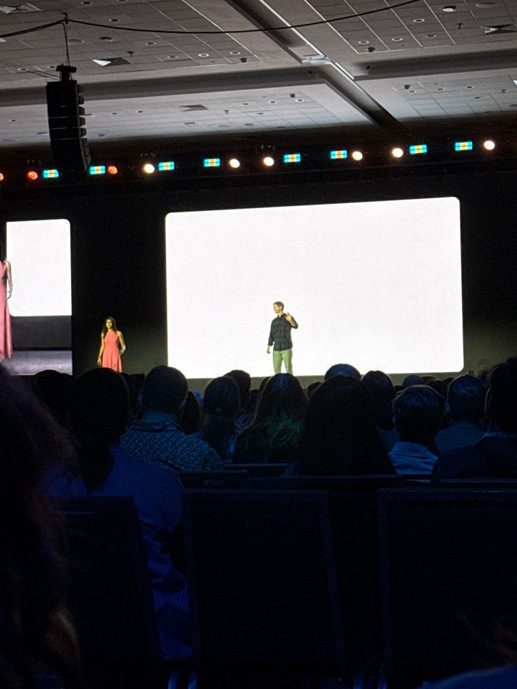 a blank canvas being projected behind two speakers
