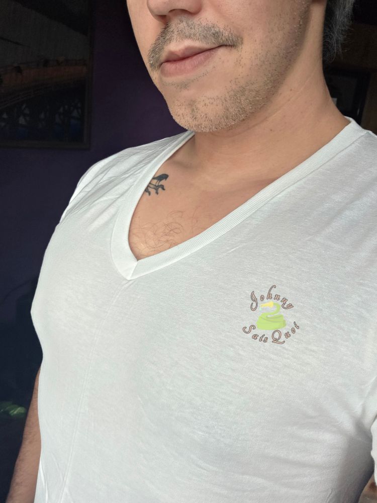 A man in a white v neck shirt, with a little tuft of grey chest hair exposed.