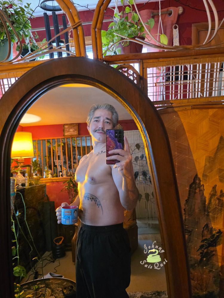 A grey haired man shirtless taking a mirror selfie.