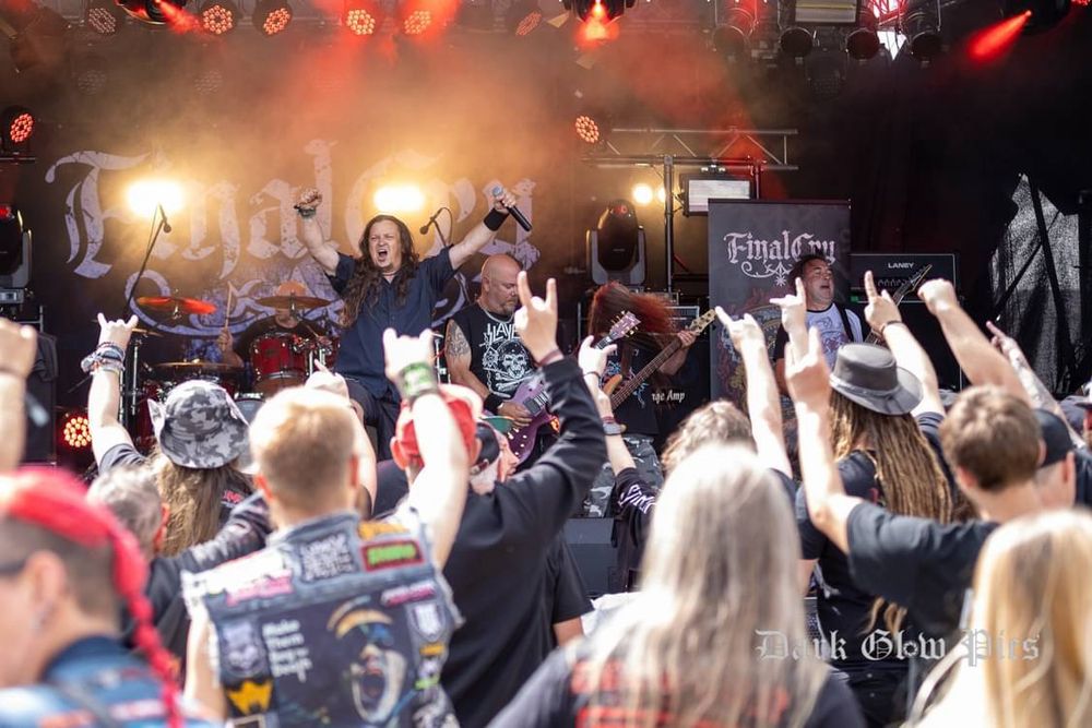 Final Cry on stage, you can see a front of stage photo with the band, some lights behind of hands (with devil horns) up in the air.
