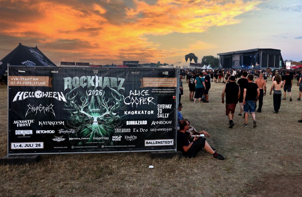 Werbeplakat für das ROCKHARZ 2026 auf dem Infield. Im Hintergrund die Bühne, der Himmel hat eine abendrötliche Färbung. Auf dem Plakat sind die Logos der bisher angekündigten Bands. U.a. neben Alice Cooper, Helloween, Emperor auch FINAL CRY