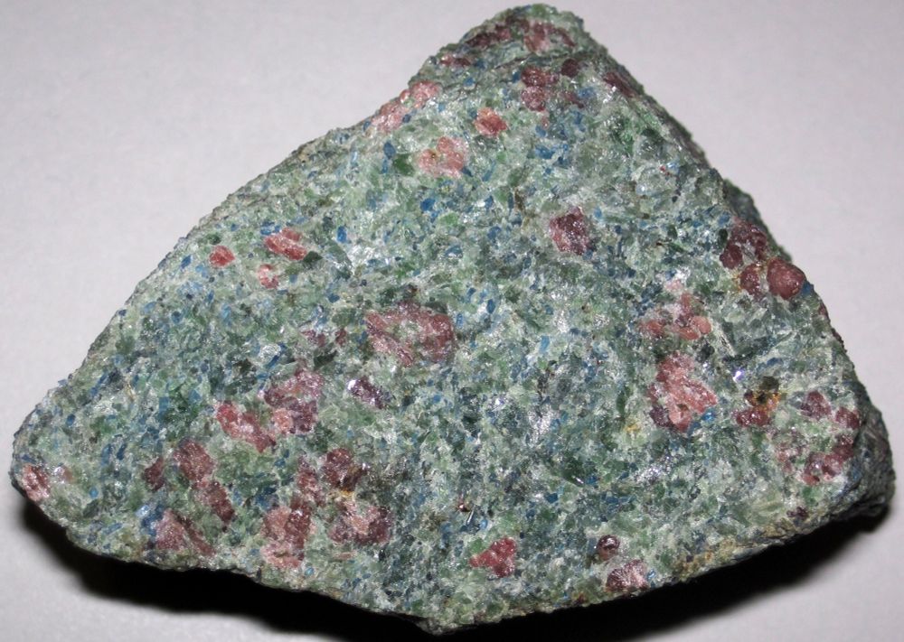 A coarse-grained eglogite with green pyroxene, red garnet, and - unusually - deep blue kyanite.

"The eclogite seen here is from the Eastern Alps in Slovenia. It has a kyanite component. The resulting rock is red and green and blue - a remarkable color combination."

photo credit James St. John, https://www.flickr.com/photos/jsjgeology/52736773607/