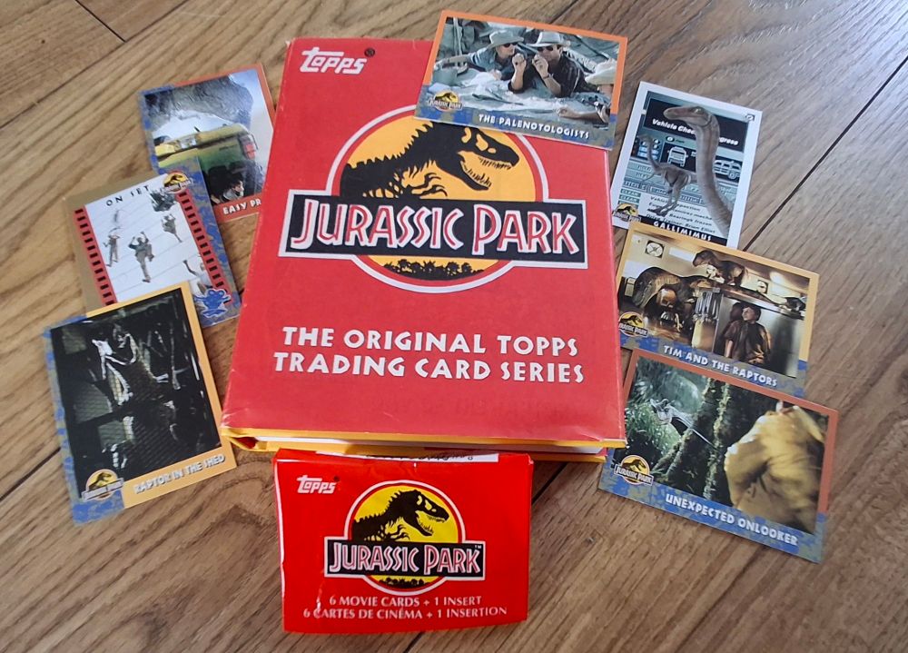 A small book for Jurassic Park Topps Trading Card Series is surrounded by 7 cards featuring images of dinosaurs and the cast of the 1993 film.