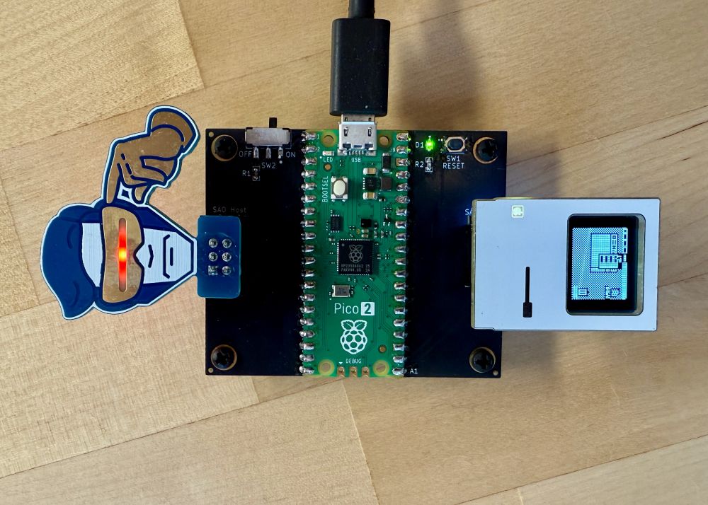 A PCB hosting a Raspberry Pi Pico 2 board with a couple Simple Add-on (SAO) boards plugged in.