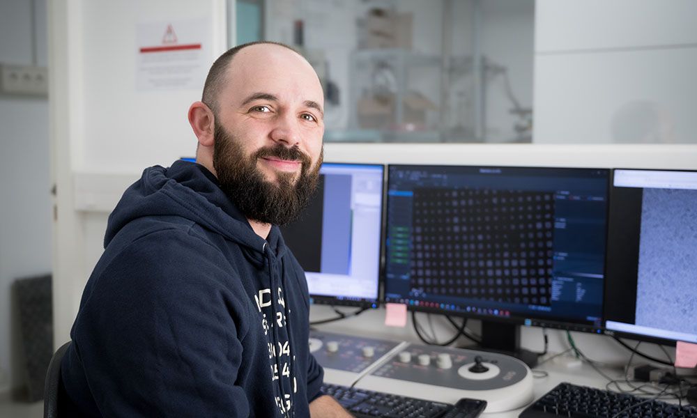 Portrait picture of Romain Linares, with computers in the background.